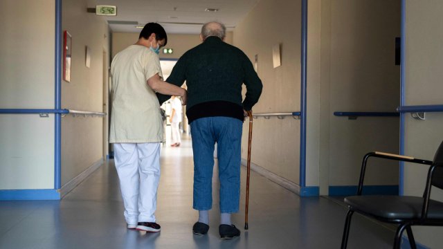 Article thumbnail: An elderly care home resident walks with an employee at the public EHPAD "Pays Vert" in Mauriac, central France, on March 23, 2022. (Photo by Thierry ZOCCOLAN / AFP) (Photo by THIERRY ZOCCOLAN/AFP via Getty Images)