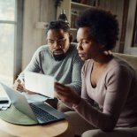 Article thumbnail: Worried African American couple paying their finances over a computer at home. Focus is on man.