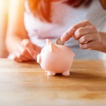 Article thumbnail: Woman putting coins to piggi bank.