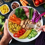 Article thumbnail: Healthy eating and diet concepts. Colorful and healthy fresh salad on rustic wood table. Included ingredients: Chicken, tomatoes, broccoli, lettuce, bell peppers, mushroom, carrots, radicchio, almonds.