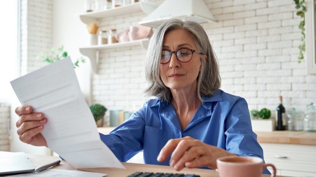 Article thumbnail: Senior mature business woman holding paper bill using calculator, old lady managing account finance, calculating money budget tax, planning banking loan debt pension payment sit at home kitchen table.