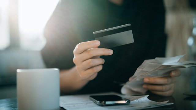 Article thumbnail: Cropped shot of young Asian woman holding credit card and expense receipts, handing personal banking and finance at home. Planning budget, calculating expenses and managing financial bills. Home budgeting. Home finances. Digital banking habits