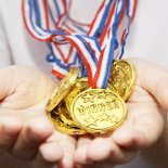 Article thumbnail: A boy with cupped hands holding gold plastic medal