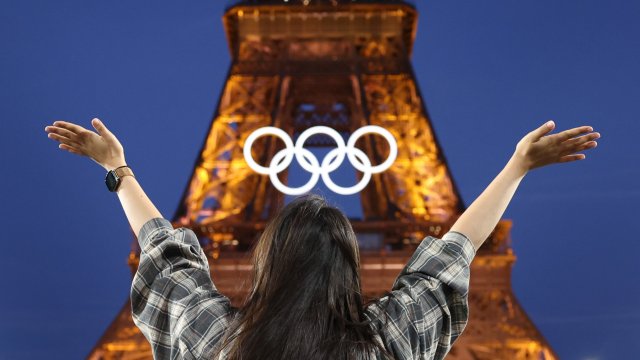 PARIS, FRANCE - JULY 21: A spectator poses in front of the Eiffel Tower and the Olympic rings on July 21, 2024 in Paris, France. The city is gearing up to host the XXXIII Olympic Summer Games from July 26 to August 11. (Photo by Christian Petersen/Getty Images)