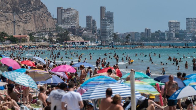 Article thumbnail: ALICANTE, SPAIN - 2024/07/14: Tourists and locals cool off swimming and sunbathing at a crowded El Postiguet Beach during a summer day. The Tourism Ministry has predicted that 41 million international tourists are expected to visit Spain this summer setting a new record. (Photo by Marcos del Mazo/LightRocket via Getty Images)